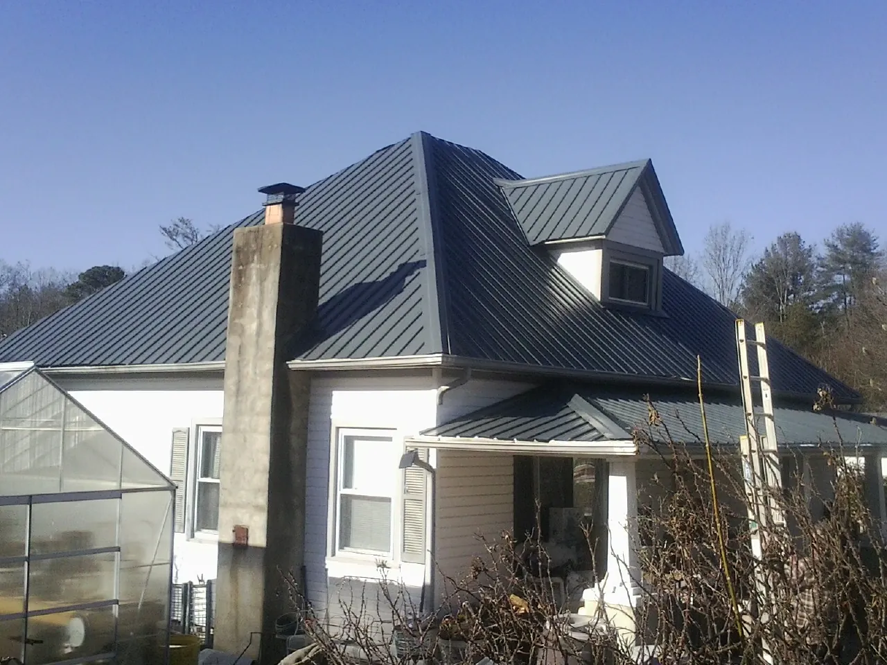 Dark blue standing seam metal roof on a white farmhouse with dormer — Slate & Tile Roof Repair by Roofing Brothers in Carbondale