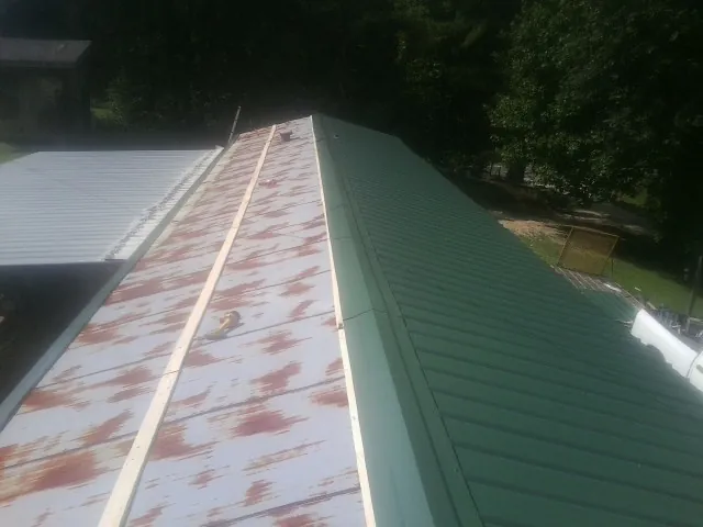 Old rusted panels beside newly installed green metal roofing — Wind Damage Roof Repair by Roofing Brothers in Carbondale