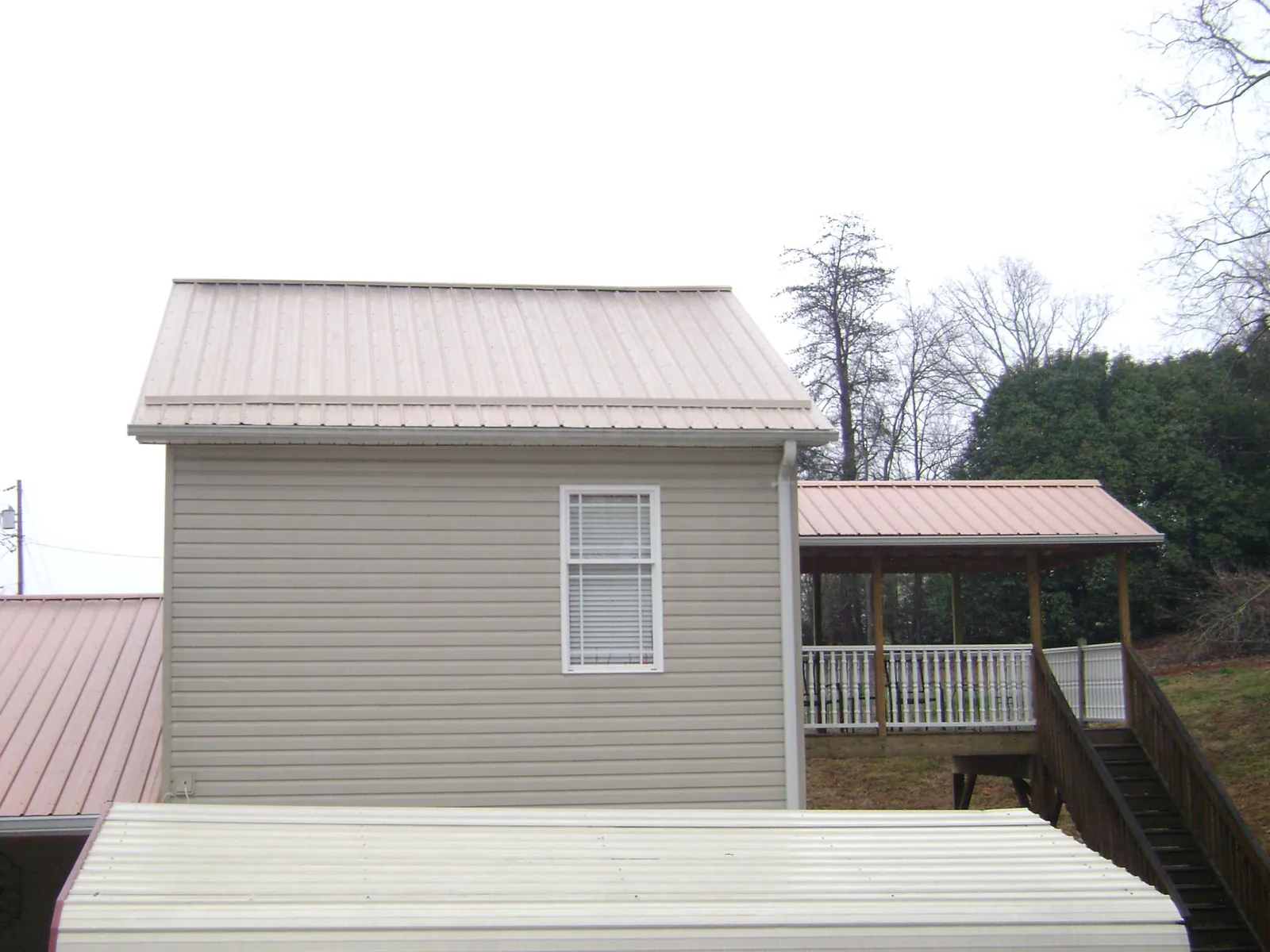 Tan metal roofs on a two story addition and attached porch, from a Roof Replacement job in Carbondale